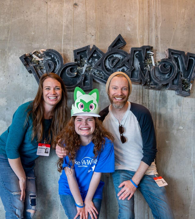 Selah in front of Pokemon sign with parents