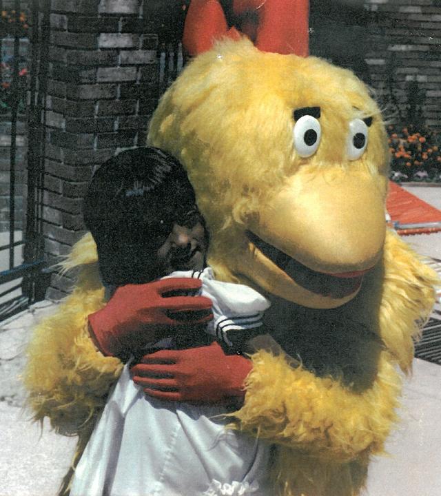 Girl hugging chicken mascot 
