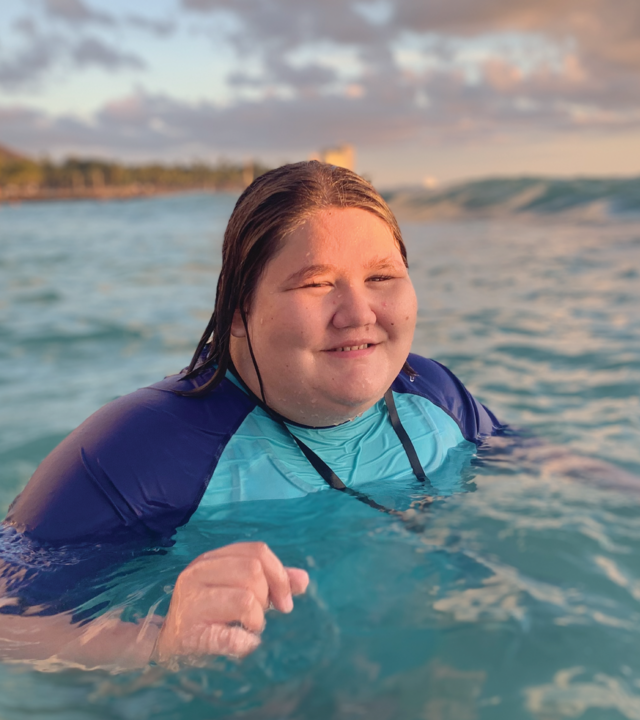 Rusha swims in the Hawaiian ocean waters and smiles