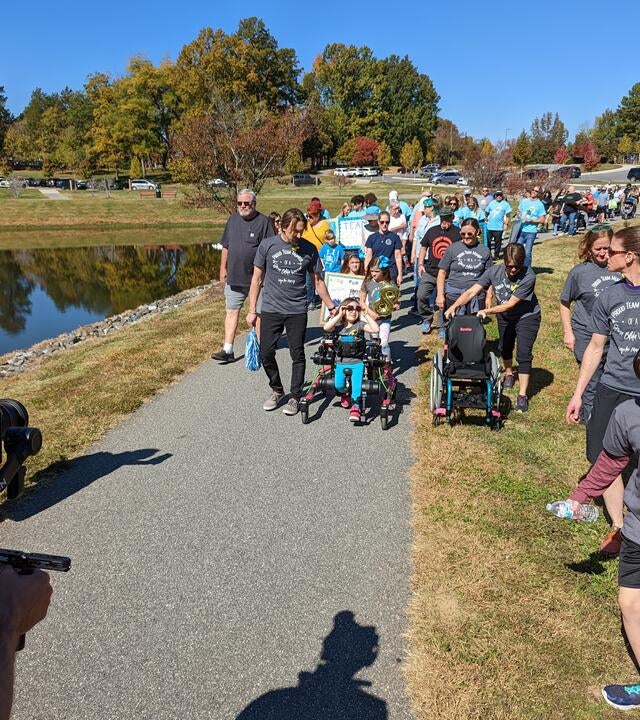 Wish kid Marcy pictured front center walking in her pink Trexo with a large group following behind her