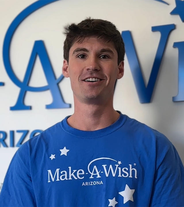Ben Posorske stands in front of the Make-A-Wish Arizona wish wall.