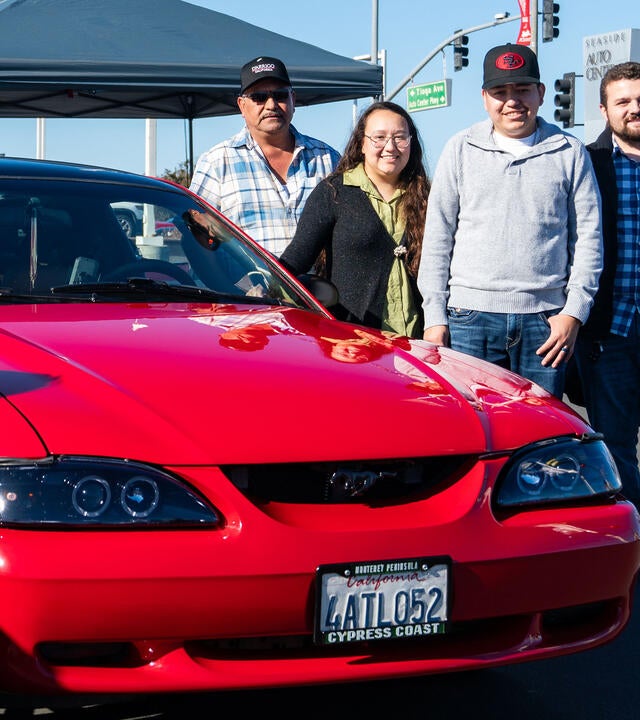 Ignacio with his family during his wish reveal standing next to his restore Mustang