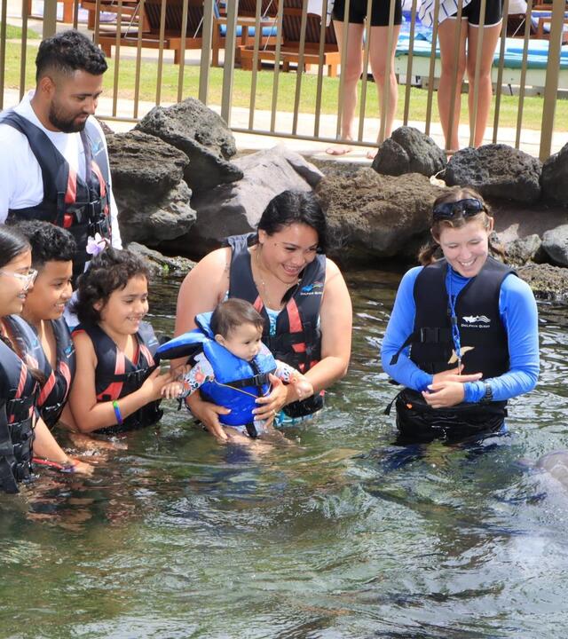 Deydalie and her family feed the dolphins.