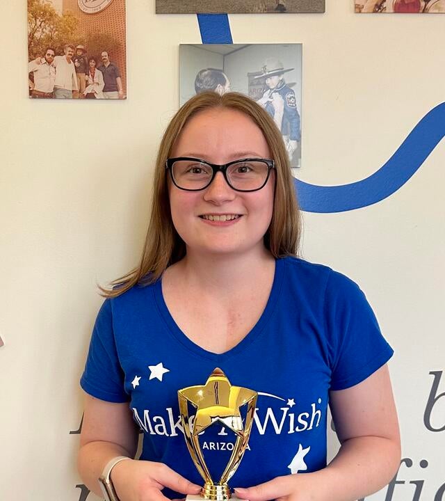 Abbie Tremp stands in front of the Make-A-Wish Arizona wish wall.