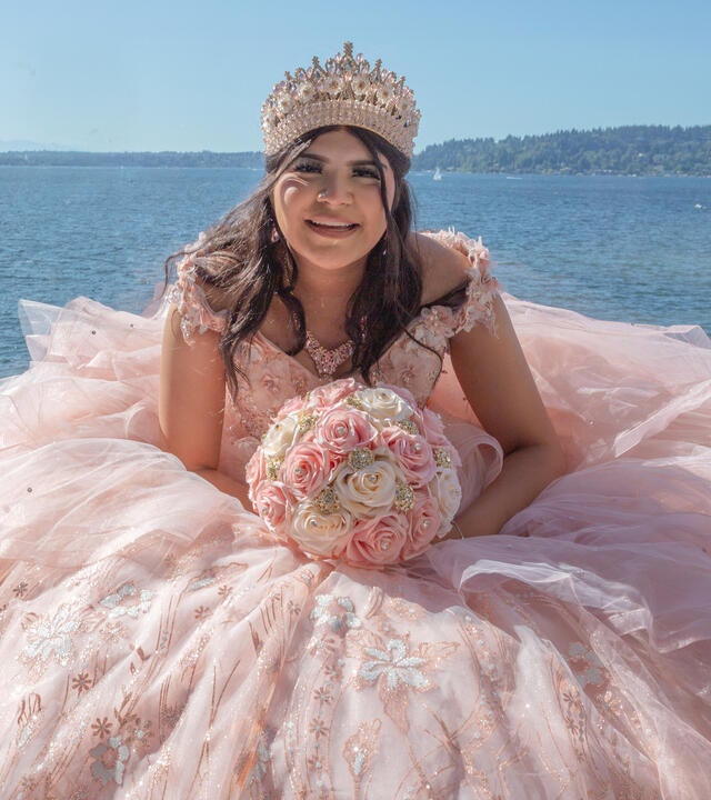 Jacqueline in a pink dress sitting at the waterfront.