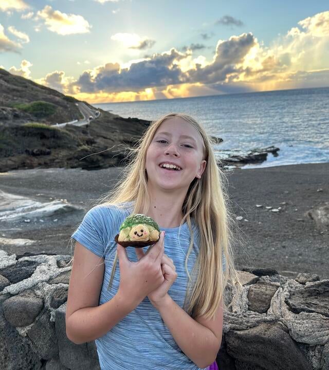 Wish kid Nora smiling brightly standing on a black sand beach