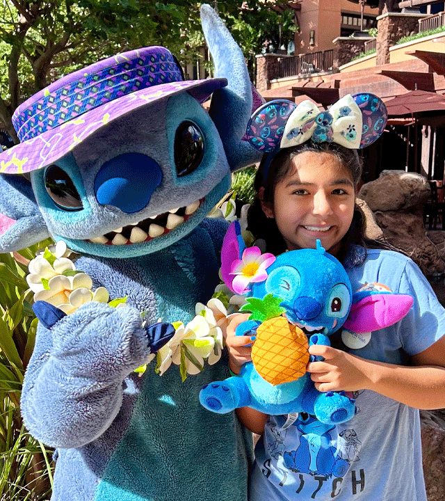 Sophia standing next to Stitch holding her Stitch stuffed animal