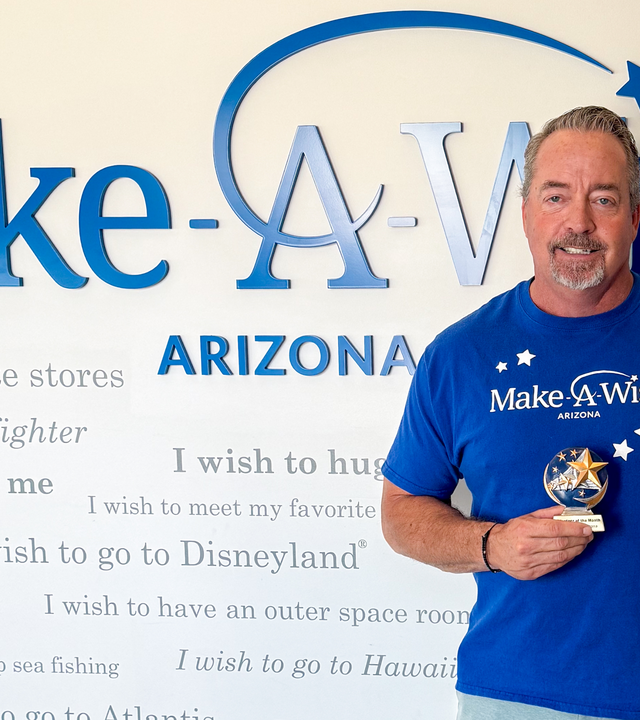 Duke Snider, June volunteer of the month, standing in front of Wish Wall