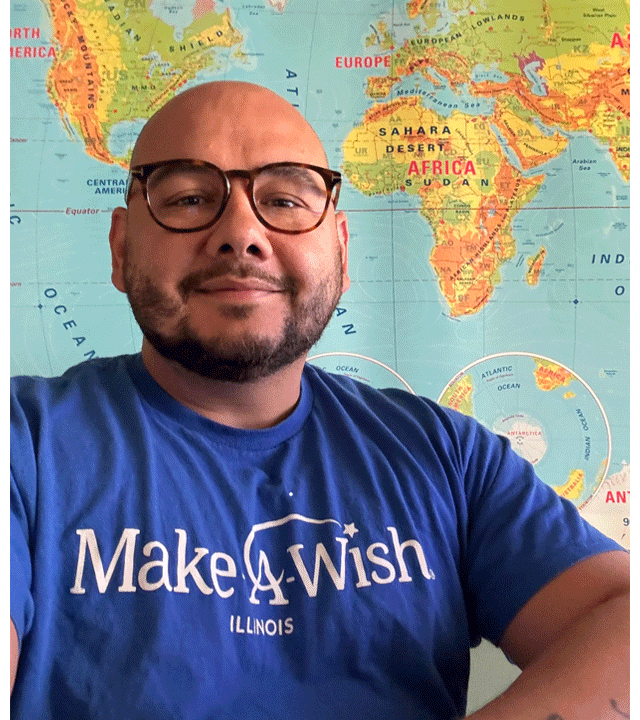 Juan smiling in front of a world map