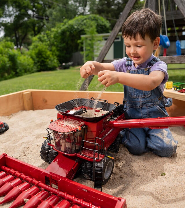 Wish kid Henry playing with a combine toy in the sandbox