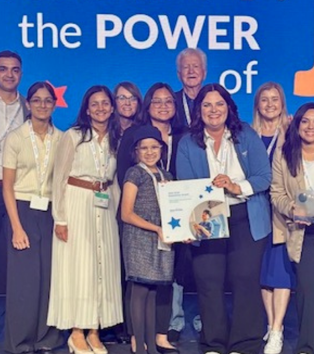 A group of people pose while holding an award. 
