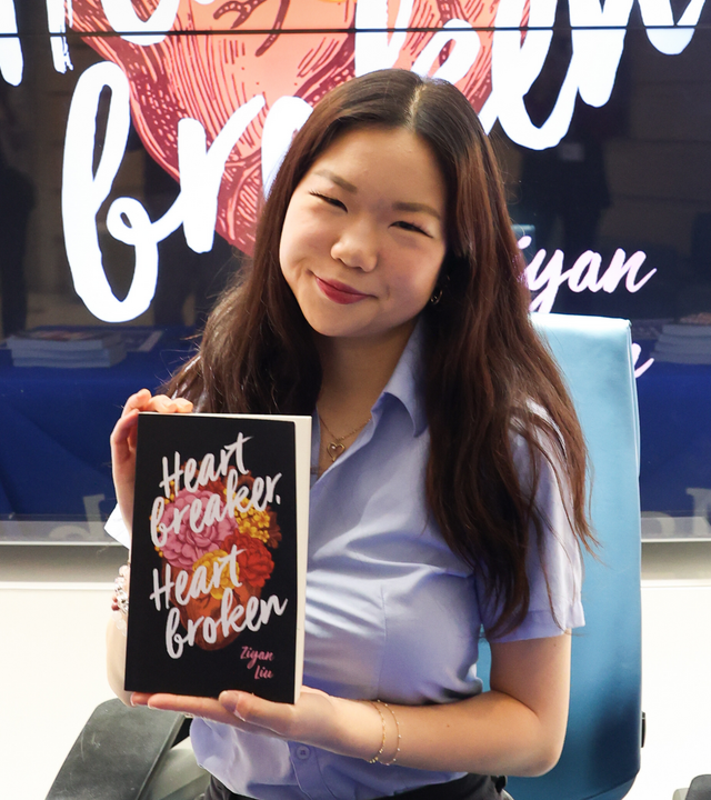 Wish kid Ziyan smiles, posing with her book during her wish celebration.