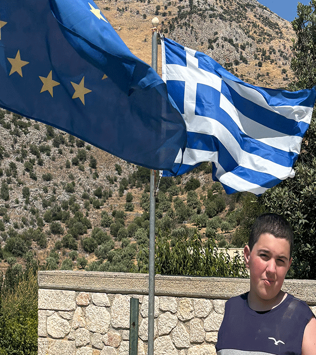 Niko standing in front of the Greek flag