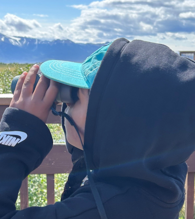 Aanya looks through binoculars on her wish trip to Alaska