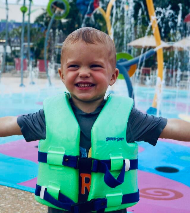 Knox at a waterpark in his life jacket with his arms stretched out