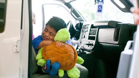 Juan hugging plush turtle during his grand welcome to Hawaii