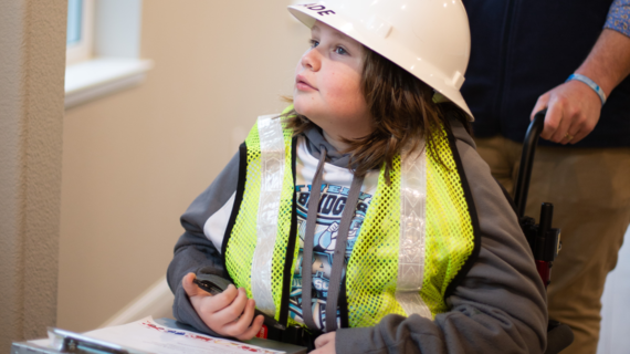 Wish Kid Cade wearing a hard hat and safety vest