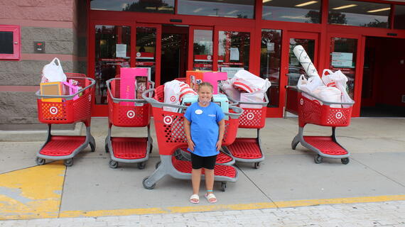 Caydence standing infront of full shopping carts 