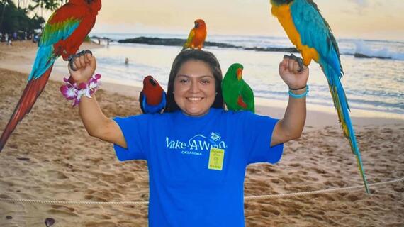 Isabelle on beach holding parrots