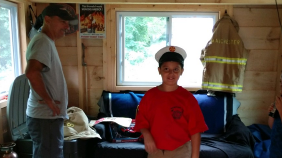 Izayah standing in his playout with a firehat on 