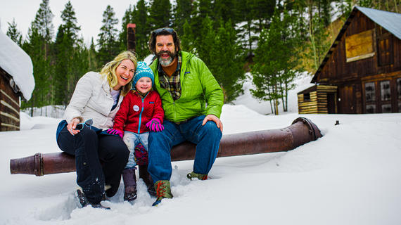 Family in the snow in front of a forest and a cabin