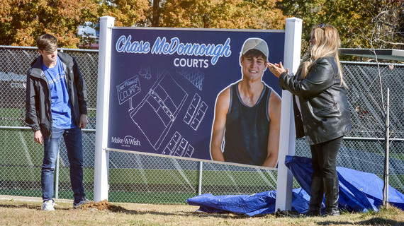 Chase sees the sign for the new tennis courts he has brought to his community.