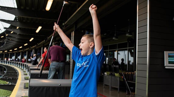 proud boy with both hands raised, holding golf club