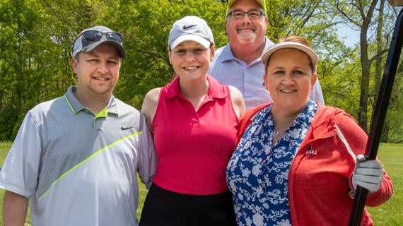 Four golfers smiling on the golf course.