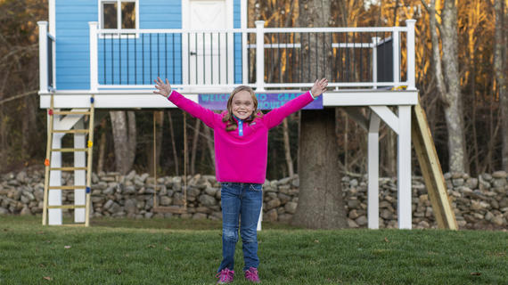 Gracie, 9, stands in front of her blue treehouse that she received for her wish.