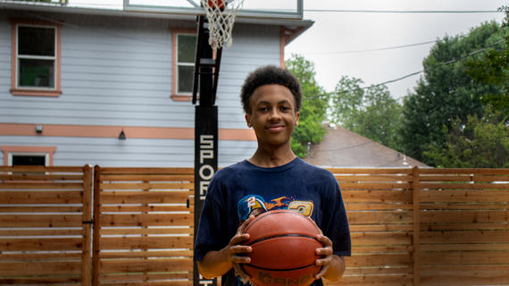 Wish Kid Solomon holding a basketball on his new basketball court