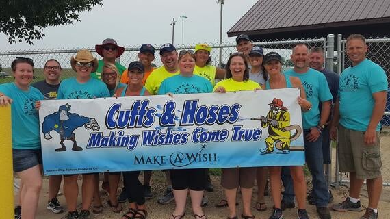 Cuffs & Hoses participants stand in front of a Cuffs & Hoses banner.