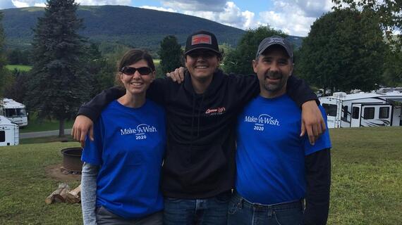 Two adults in Make-A-Wish shirts and a teenage boy in a baseball cap