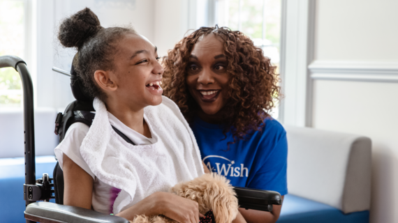 smiling child in a wheelchair with happy volunteer