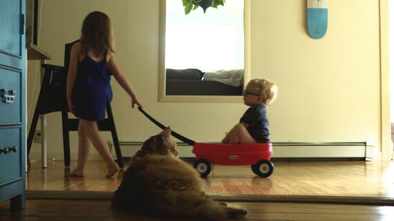 Teagan pulling Soren in their red wagon.