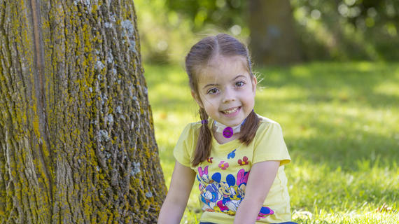 Wish kid Claire sitting by a tree smiling