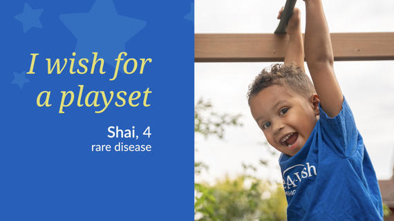 Boy in a blue Make-A-Wish t-shirt hanging from playset monkey bars