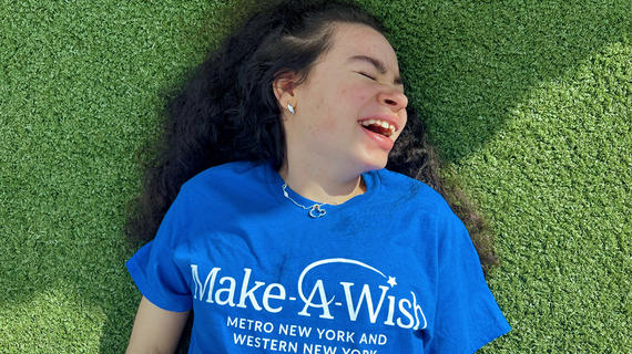 Wish kid Mariangel smiling and lying in grass