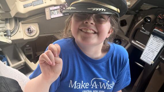 Avery S in cockpit with captains hat -Make-A-Wish Central New York