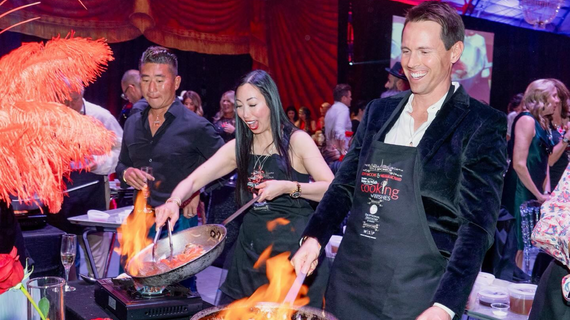 People wearing aprons and cooking at event.