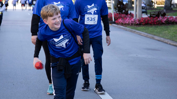 Kid smiling as he walks across the finish line at WFW
