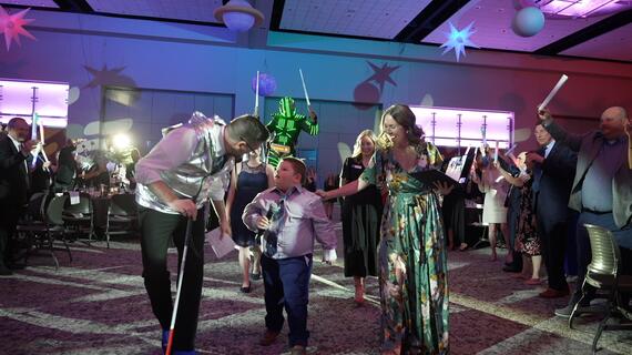 A visually impaired boy is being walked down the aisle to enter the stage where he will find out his wish is coming true!