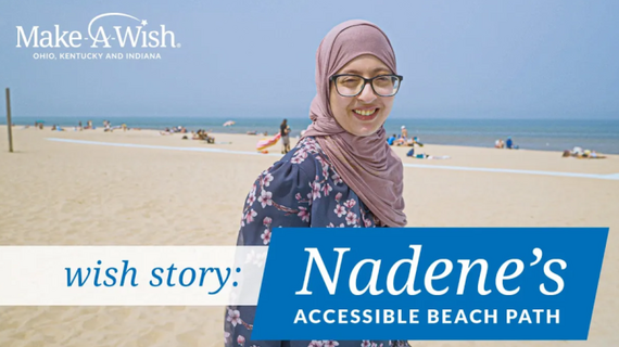 A smiling young woman wearing a hijab and glasses stands on a beach with other people in the background, with Make-A-Wish branding and text overlay "wish story: Nadene's ACCESSIBLE BEACH PATH".
