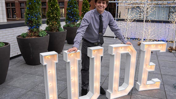 Jude standing in front his giant light up letters spelling his name - JUDE