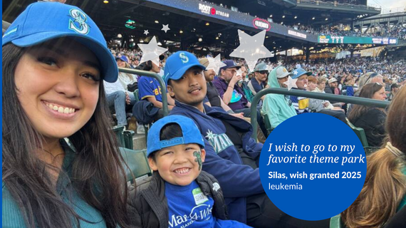 Family at Mariners game in their seats smiling at the camera 