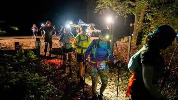 group of hikers wearing headlamps leaving for hiking trail in the dark 