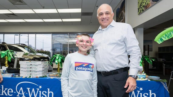 Photo shows wish kid next to adult at car dealership