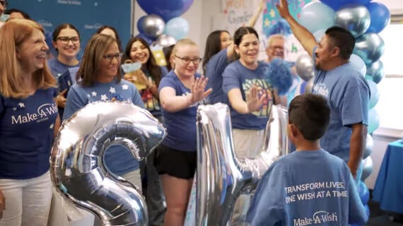 Volunteers cheer for wish kid Uriel on his wish day.