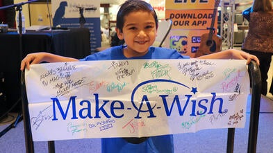 Carlos at the Laredo Radiothon holding his poster signed by all the Disney Characters