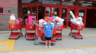 Caydence standing infront of full shopping carts 