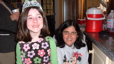 Wish Kid Lucy wearing a princess crown and Volunteer Judy holding her cake.